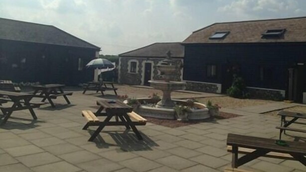 An outdoor courtyard with picnic tables, a fountain, and stone buildings. - Coach House Hotel (Royston)