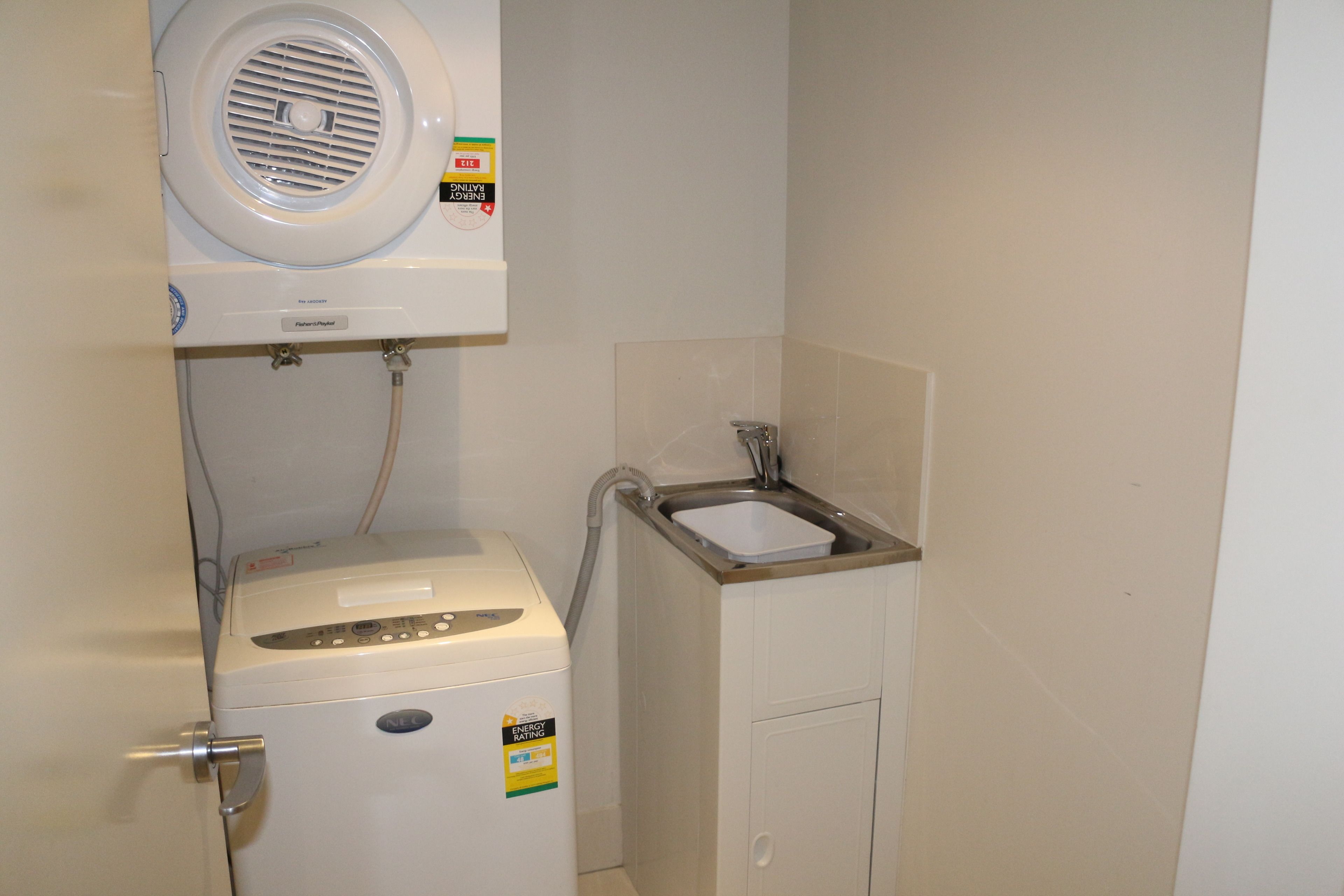 A compact laundry room with a washing machine, a dryer, and a sink.