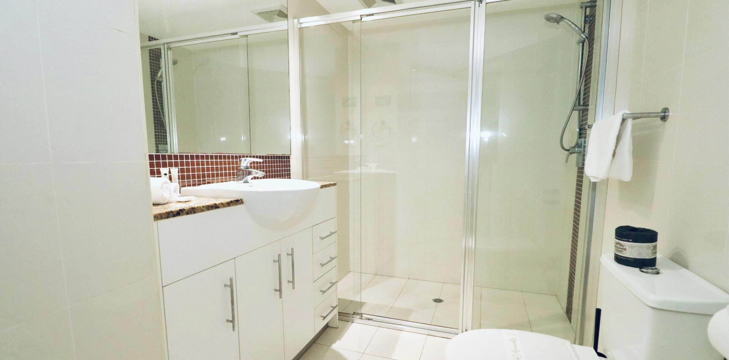 A modern bathroom with a glass-enclosed shower, a white sink, and a toilet.