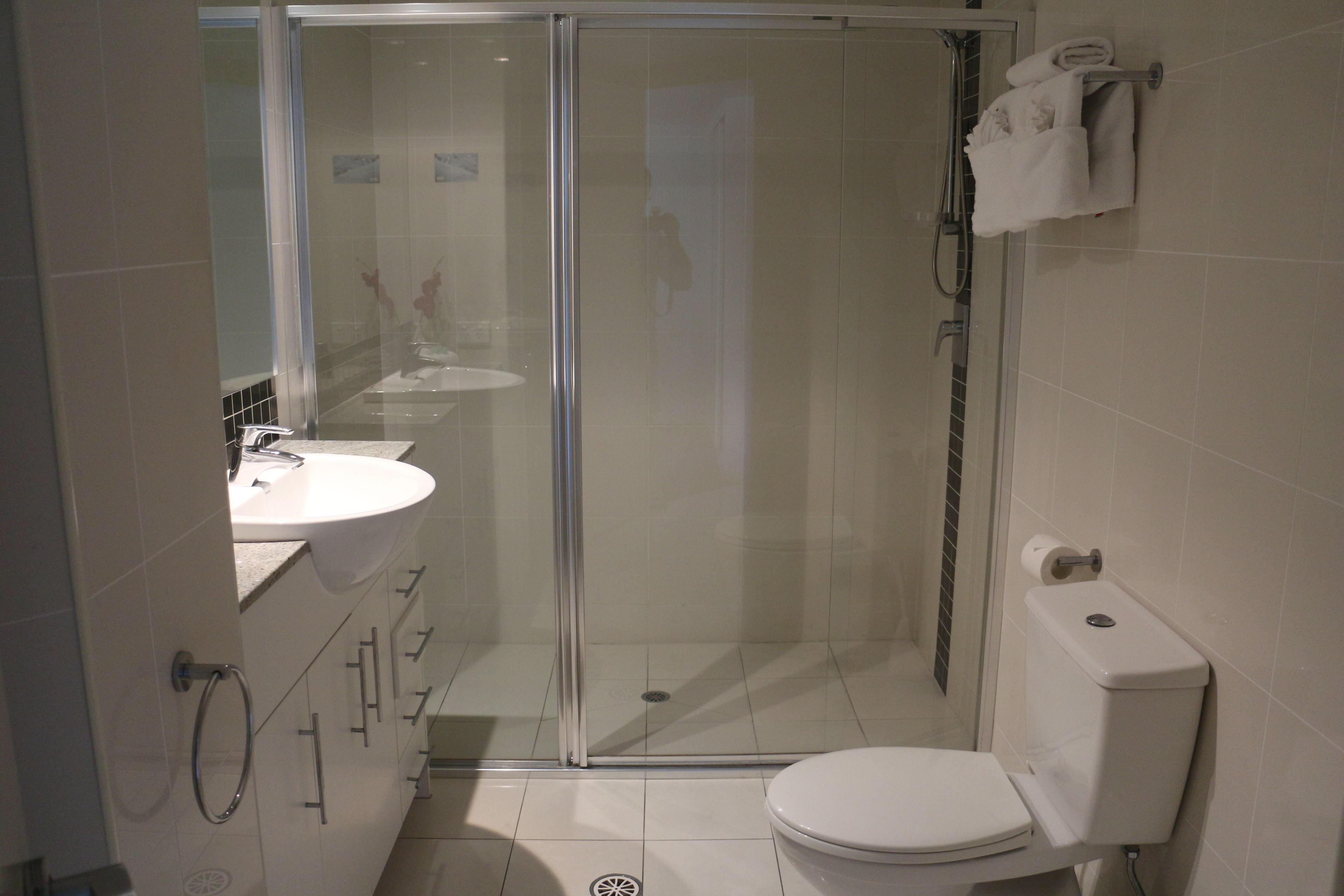 Een moderne badkamer met een douchecabine van glas, een toilet en een wastafel.