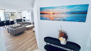 A modern living room with a sofa, coffee table, and a dining area in the background.