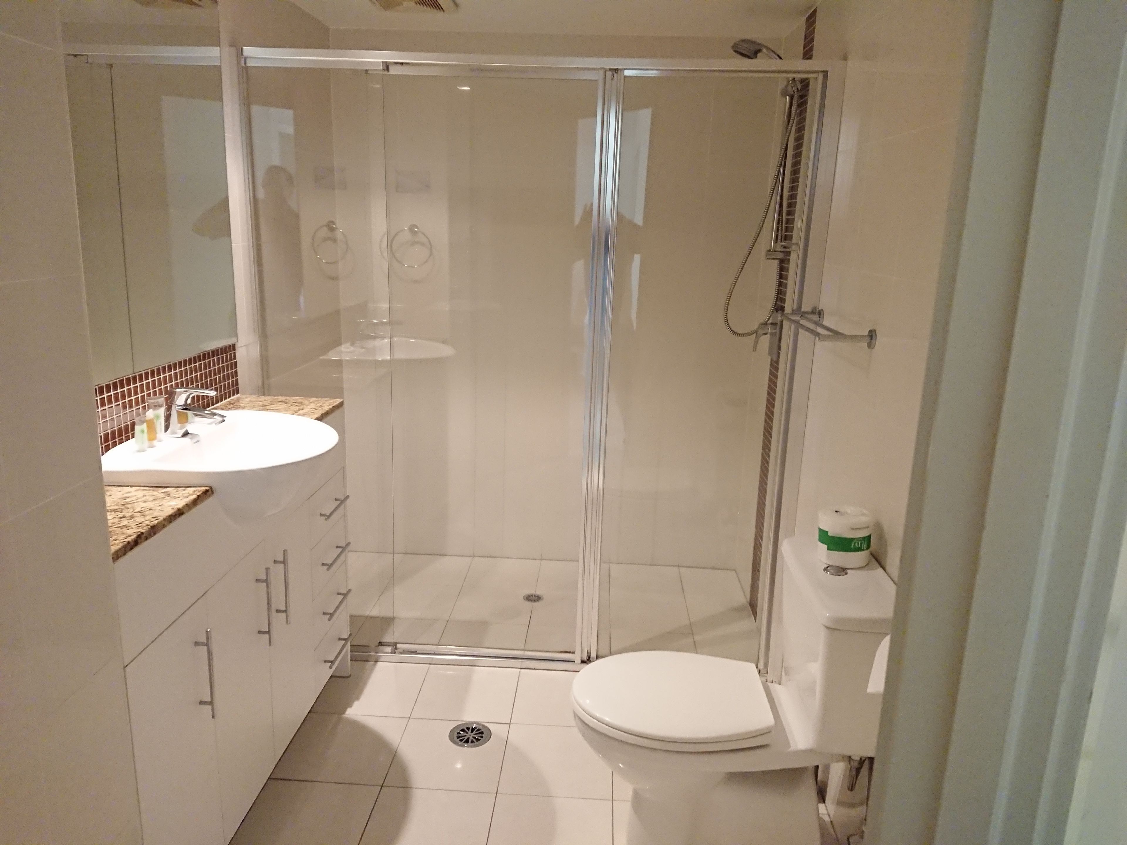 Un baño moderno con ducha de vidrio, lavamanos blanco y retrete.