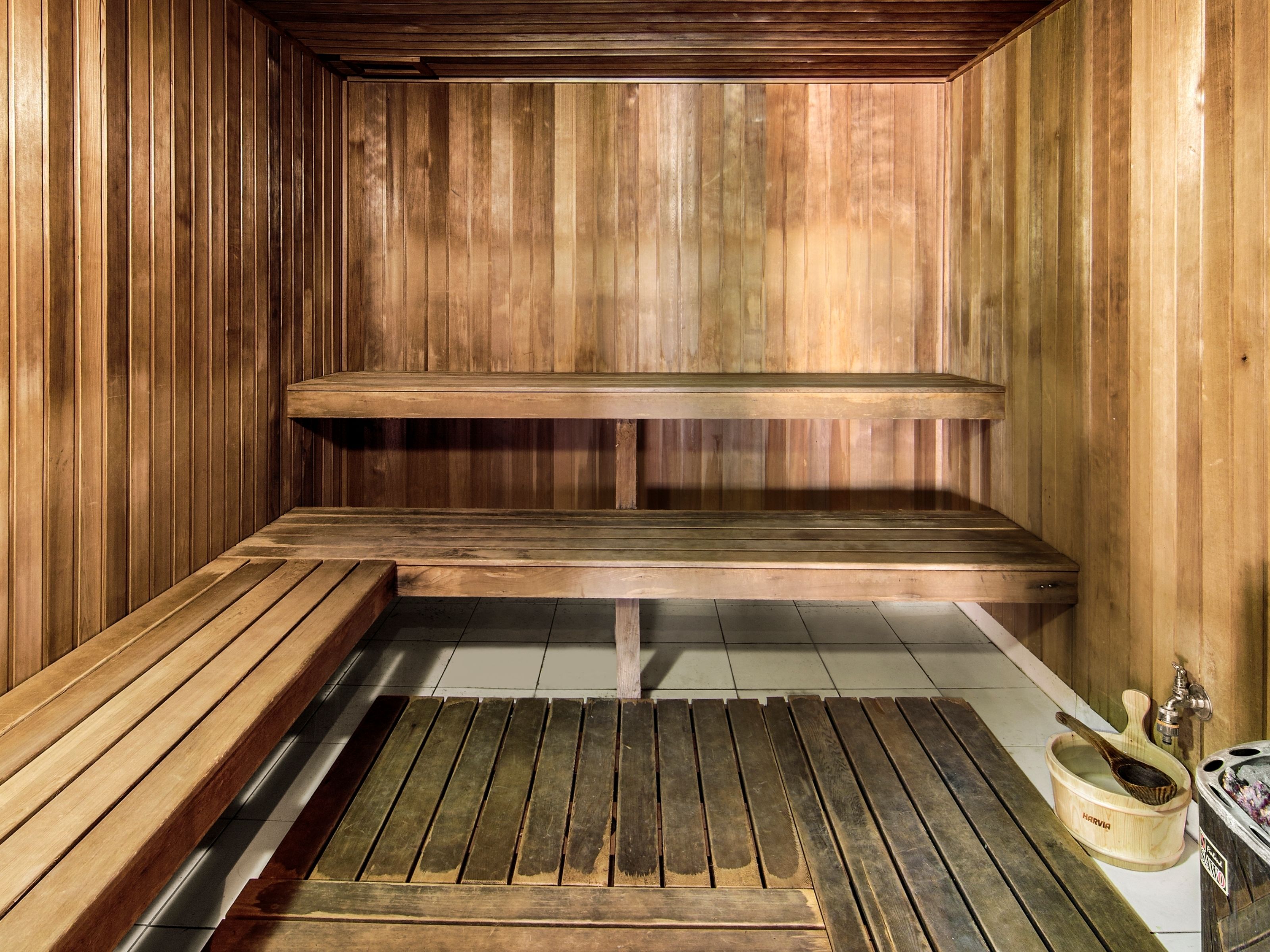 Uma sauna de madeira com bancos e uma bacia de madeira.