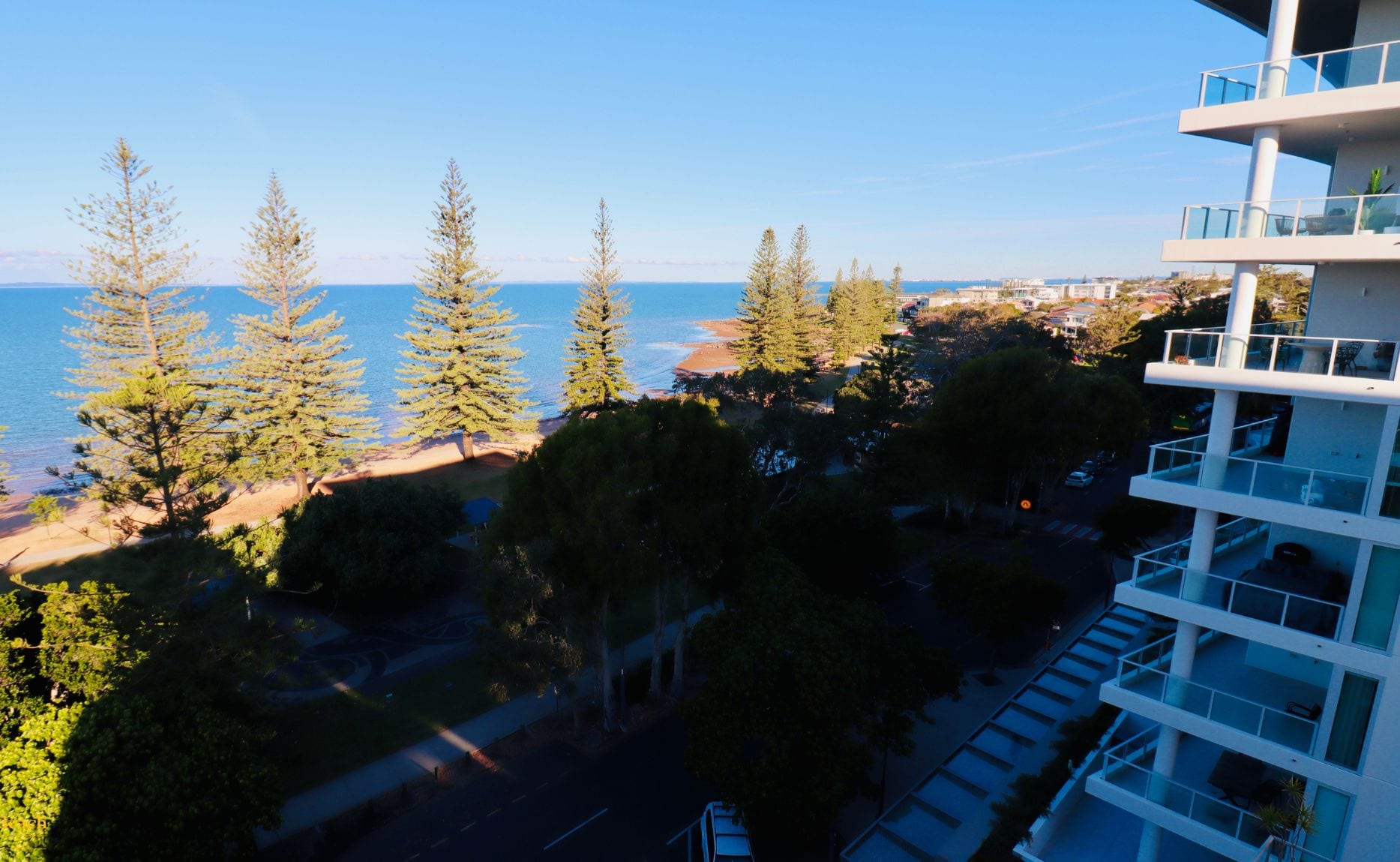 A high-rise building with a view of the sea and trees.