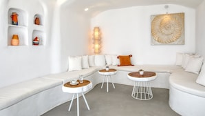 Una sala moderna con un sofá blanco, dos mesas redondas y cerámica decorativa en estanterías.