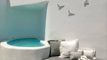 A modern, minimalist room with a built-in bathtub, a cushioned seating area, and a wall-mounted bird sculpture.
