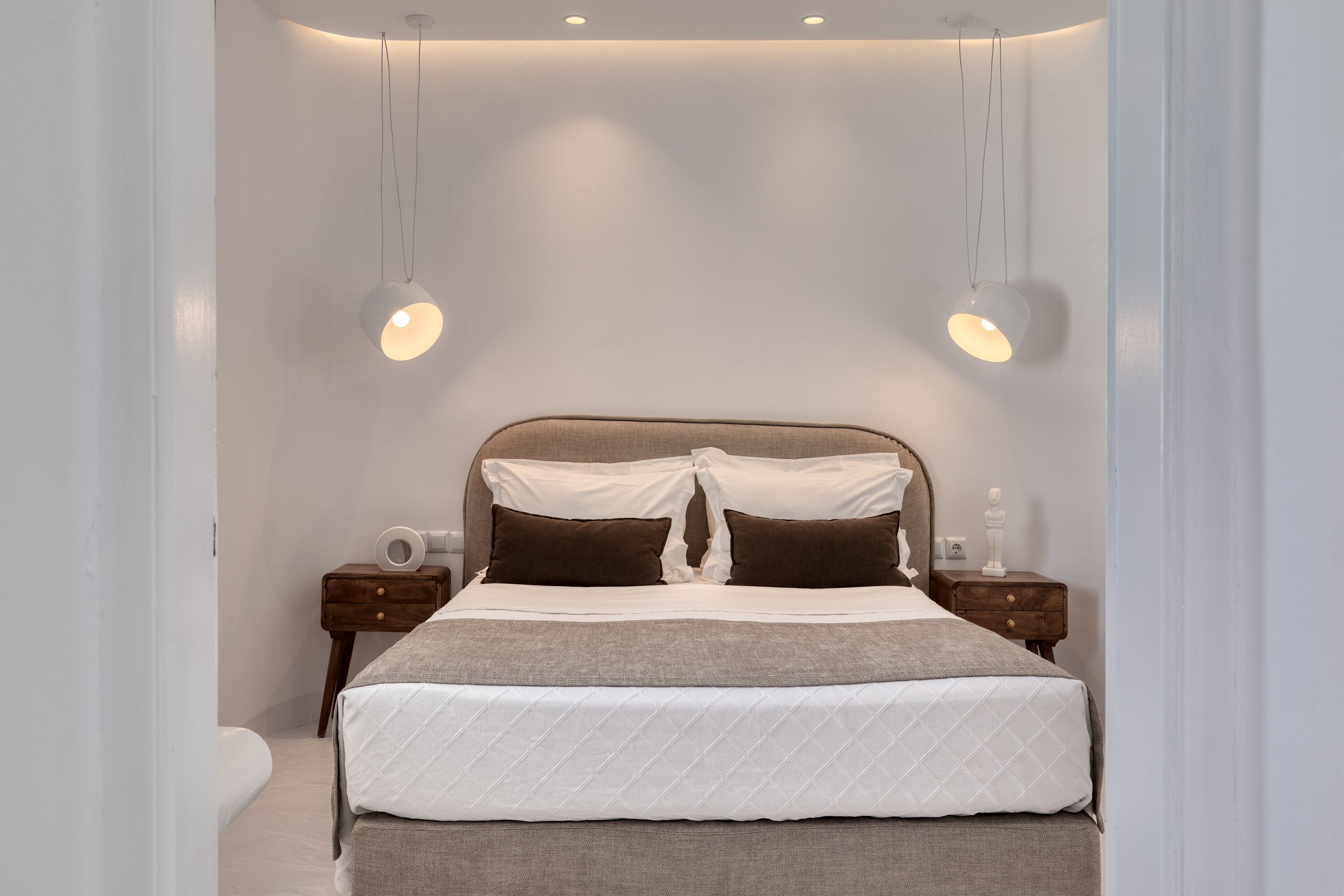A bedroom with a bed, nightstands, and a hanging light fixture.