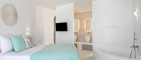 A modern bedroom with a bed, a large mirror, a flat-screen TV, and a bathroom with a bathtub and sink.