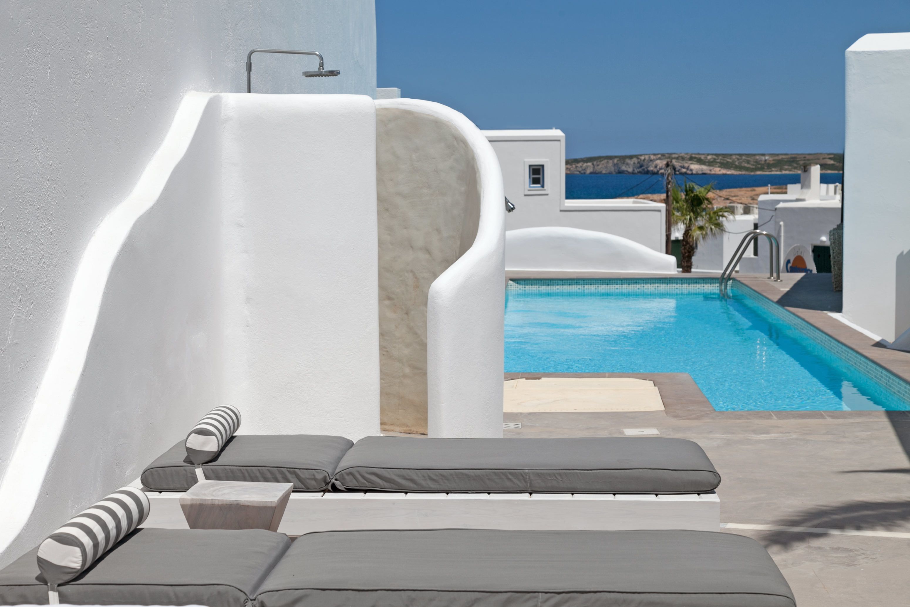 A poolside area with lounge chairs and a view of the sea.