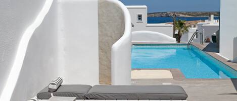 A poolside area with lounge chairs and a view of the sea.