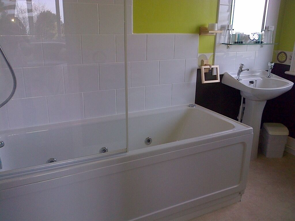A bathroom with a bathtub, a sink, and a mirror.