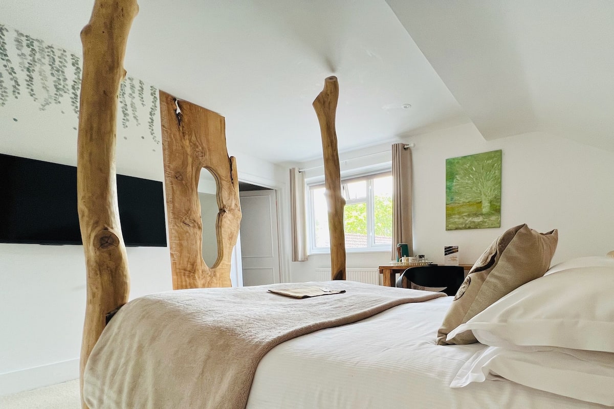 A bedroom with a large bed, wooden headboard, and a view of the outdoors.