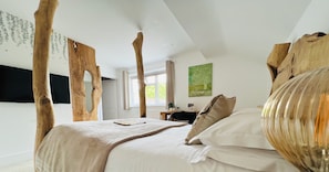 Une chambre avec un grand lit, une tête de lit en bois et une vue sur l’extérieur.