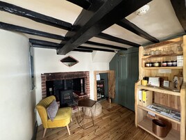 A cozy room with a fireplace, wooden furniture, and a shelf with jars.