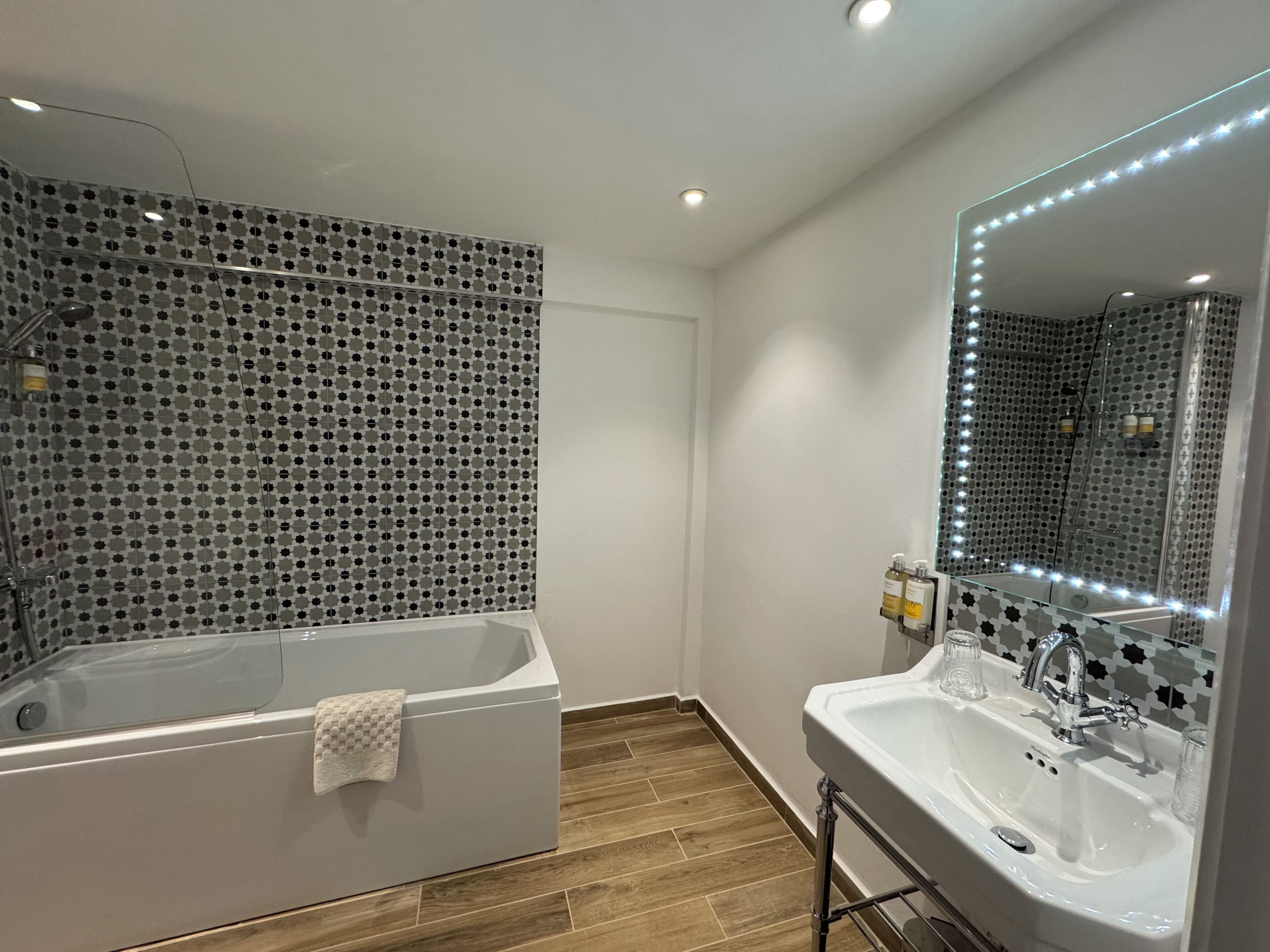 A modern bathroom with a freestanding bathtub, a large mirror with LED lights, and a sink with a vanity.