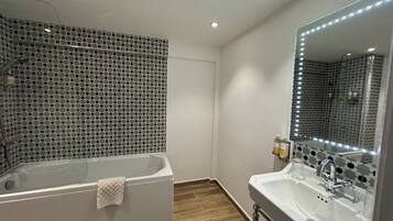 A modern bathroom with a freestanding bathtub, a large mirror with LED lights, and a sink with a vanity.
