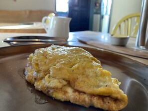 Un plat de petit-déjeuner sur une assiette, avec une tasse et un petit bol en arrière-plan.