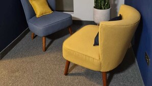 A modern room with a blue sofa and a yellow armchair, a potted plant, and a gold pendant light. - La Gruta (Arequipa)