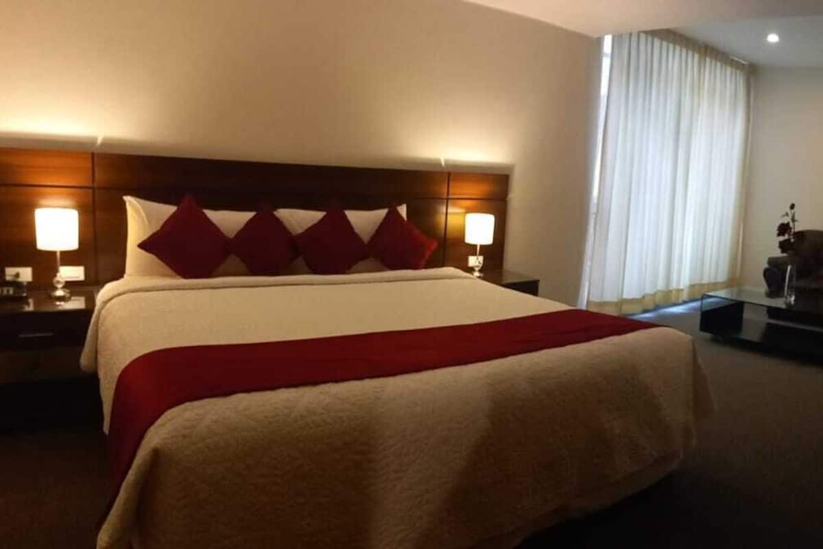 A hotel room with a large bed, a desk, a chair, and a TV.