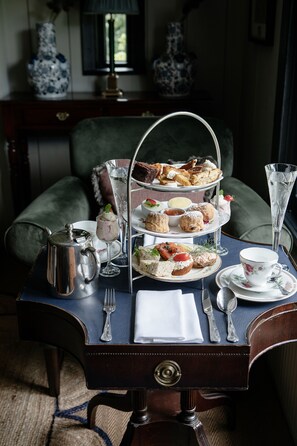 A three-tiered tea service set on a table with a vintage design, accompanied by a teapot, cups, and saucers. - Station House Hotel (Kilmessan)