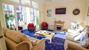 A living room with a star-patterned carpet, a fireplace, and a television mounted on the wall.
