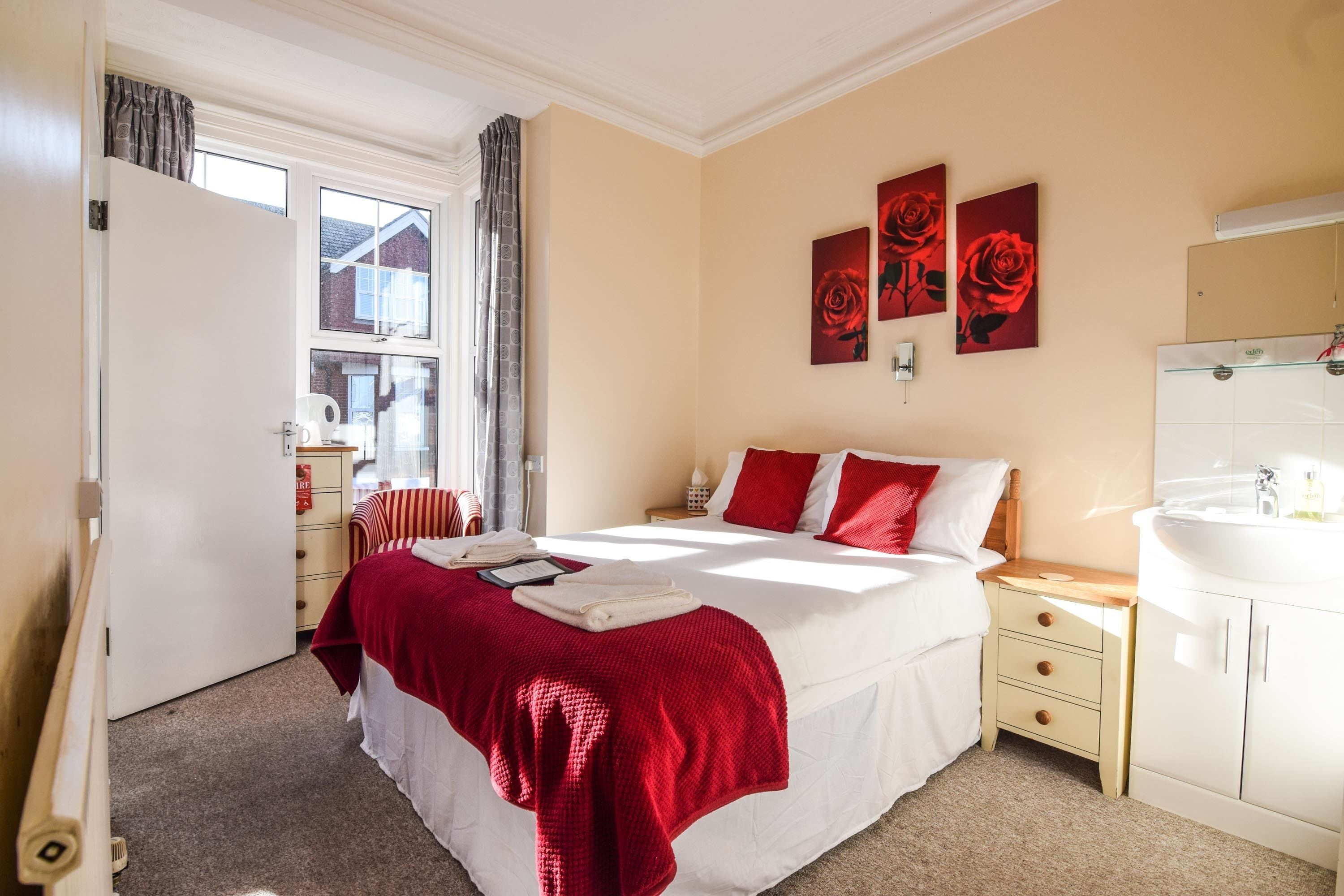 A bedroom with a bed, a bedside table, a wardrobe, and a window.