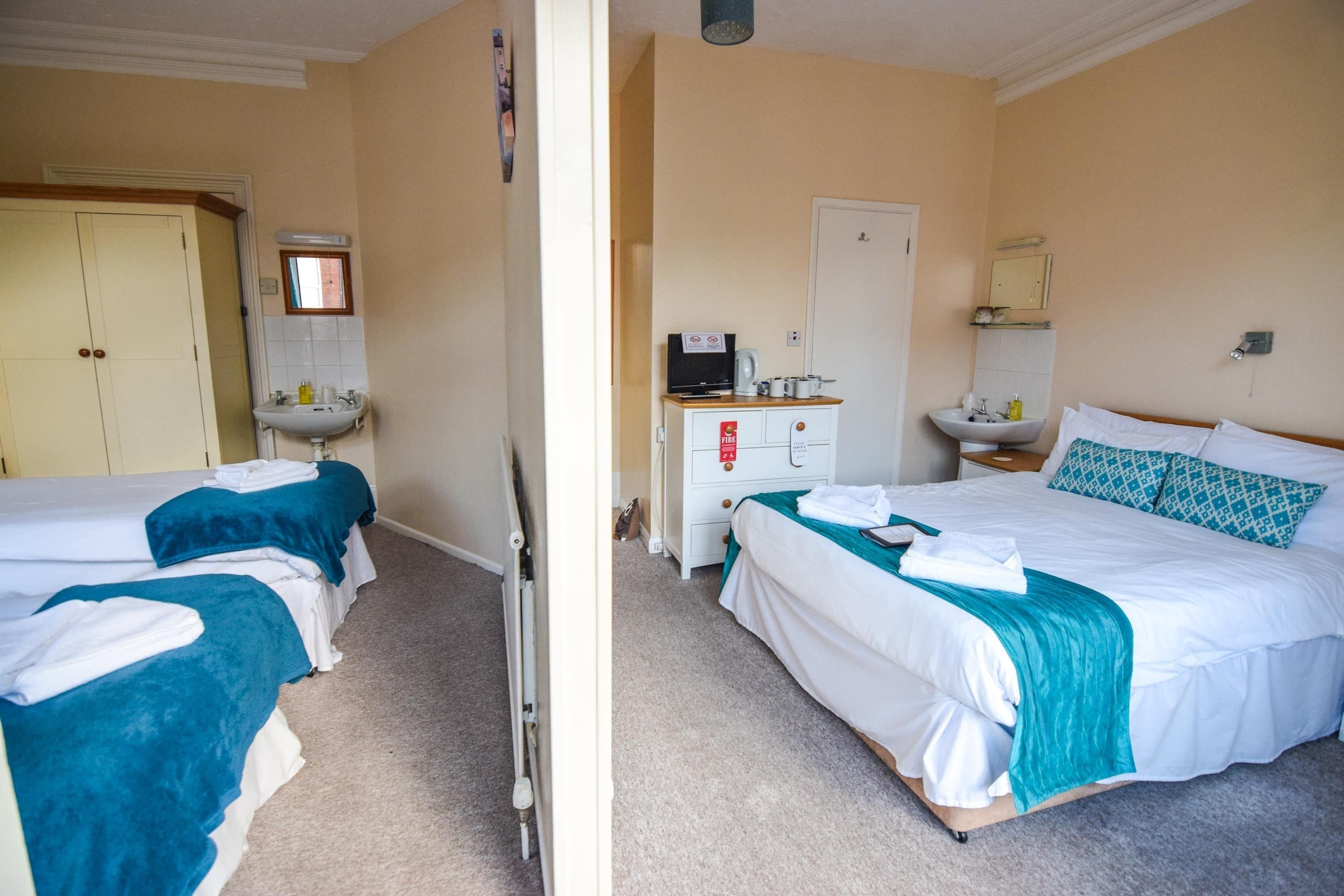 A hotel room with two beds, a bathroom, and a small kitchenette.