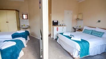 A hotel room with two beds, a bathroom, and a small kitchenette.