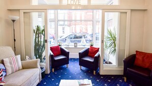 A room with a blue carpet, two armchairs, a sofa, and a coffee table.