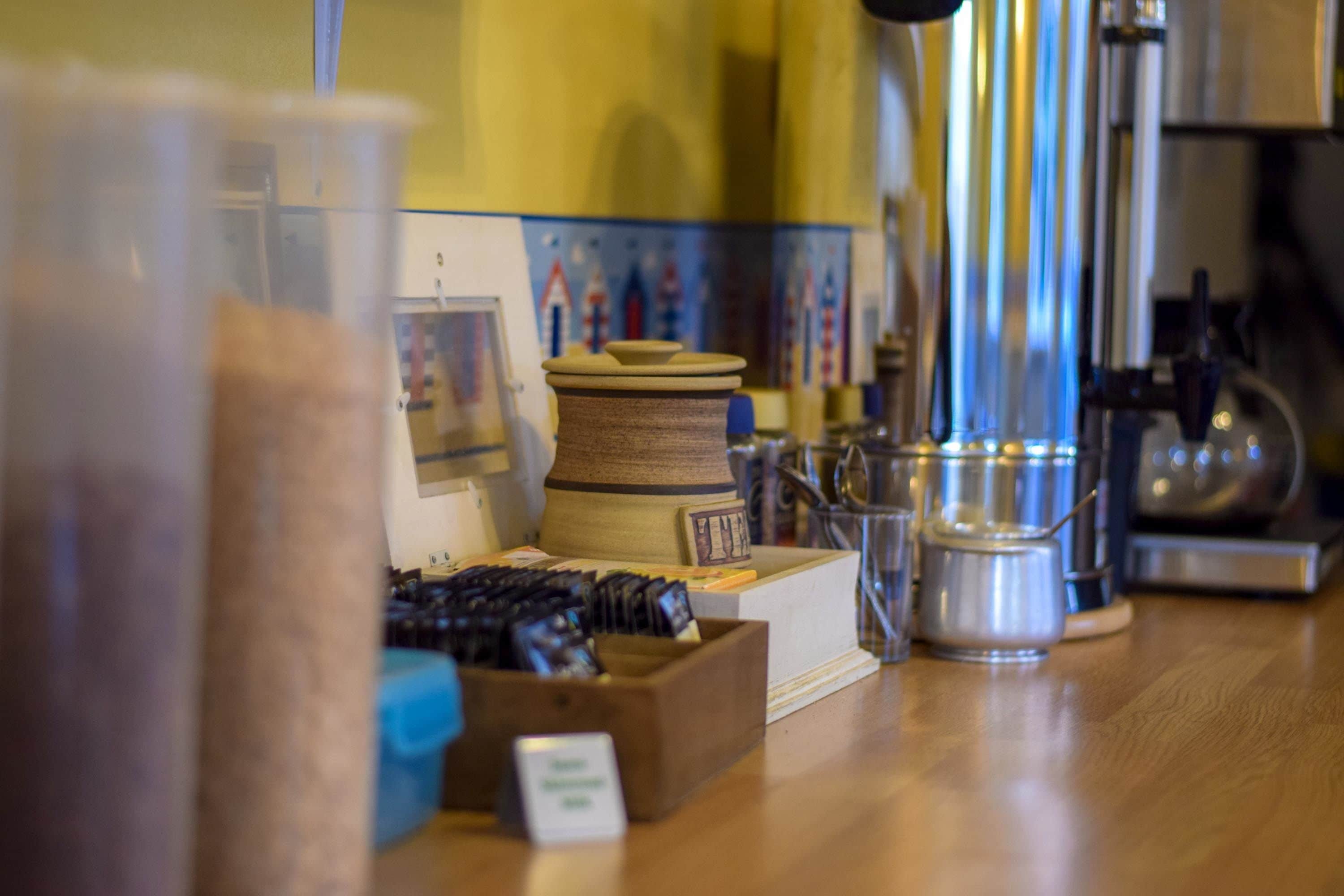 A kitchen counter with various items including a wooden box, a spool of thread, and a metal container.