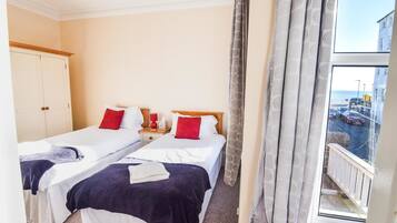 A hotel room with two beds, a window with a view of the street, and a wardrobe.