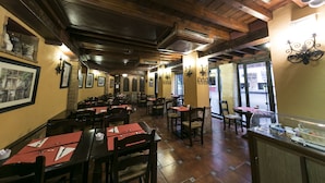 A restaurant with wooden ceilings, tiled floors, and tables with red placemats. - Posada del Toro (Granada)