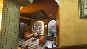 A lobby with a patterned column, a staircase, and a seating area with a view of the outside through arched windows. - Posada del Toro (Granada)