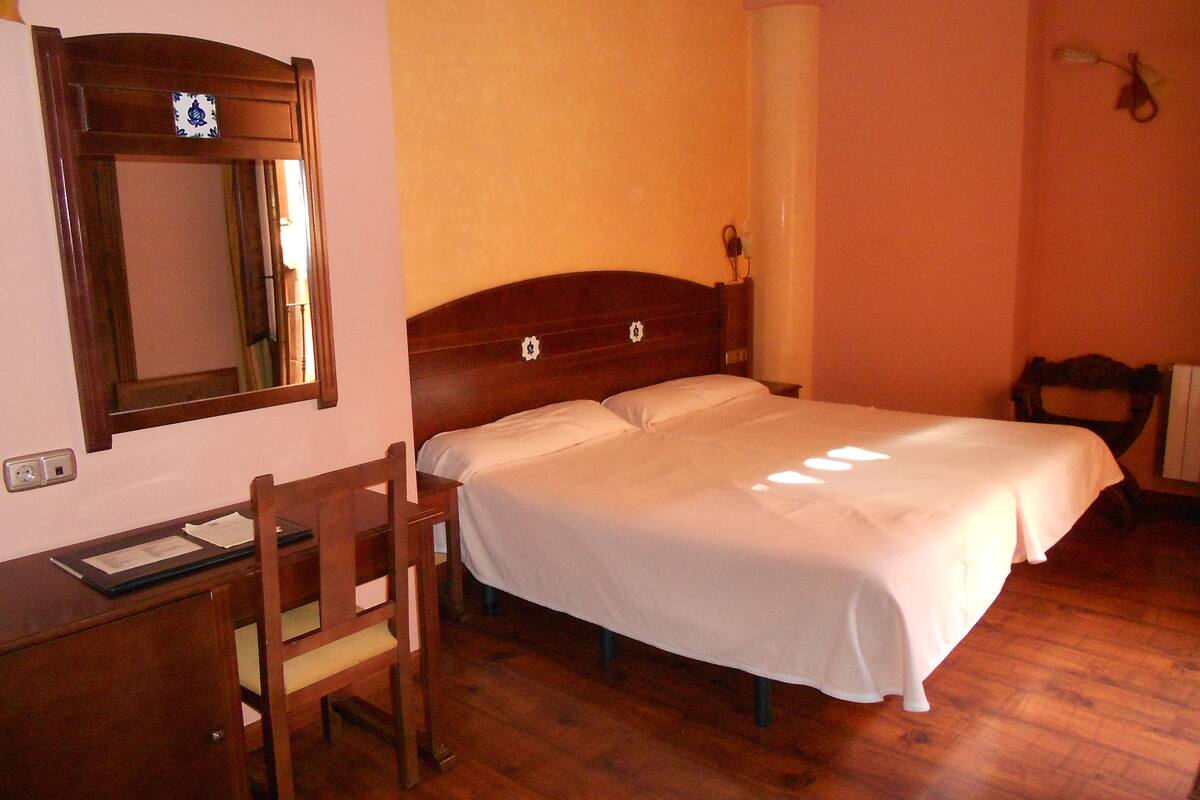 A bedroom with a wooden bed, a desk, and a chair.