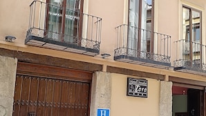 A building with a large wooden gate, balconies with metal railings, and a sign indicating it is a hotel. - Posada del Toro (Granada)