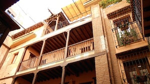 A multi-story building with balconies, wooden railings, and brick walls. - Posada del Toro (Granada)
