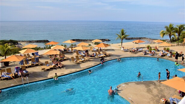 A pool area with lounge chairs and umbrellas, a clear view of the ocean, and a lifeguard tower. - Venezuela Marriott Hotel Playa Grande (Urimare)
