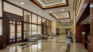 A spacious lobby with a large seating area, a reception desk, and a view of the outdoors through large windows. - Venezuela Marriott Hotel Playa Grande (Urimare)