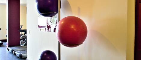 A gym with treadmills and exercise balls mounted on a wall.