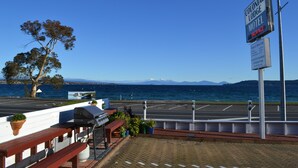 A Colonial Lodge Motel sign, a parking lot, a barbecue grill, and a view of the ocean. - Colonial Lodge Motel (Taupo)