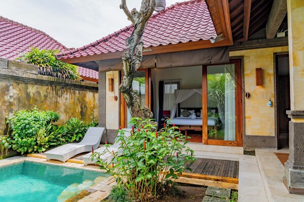 A poolside area with a lounge chair, a small pool, and a wooden deck.