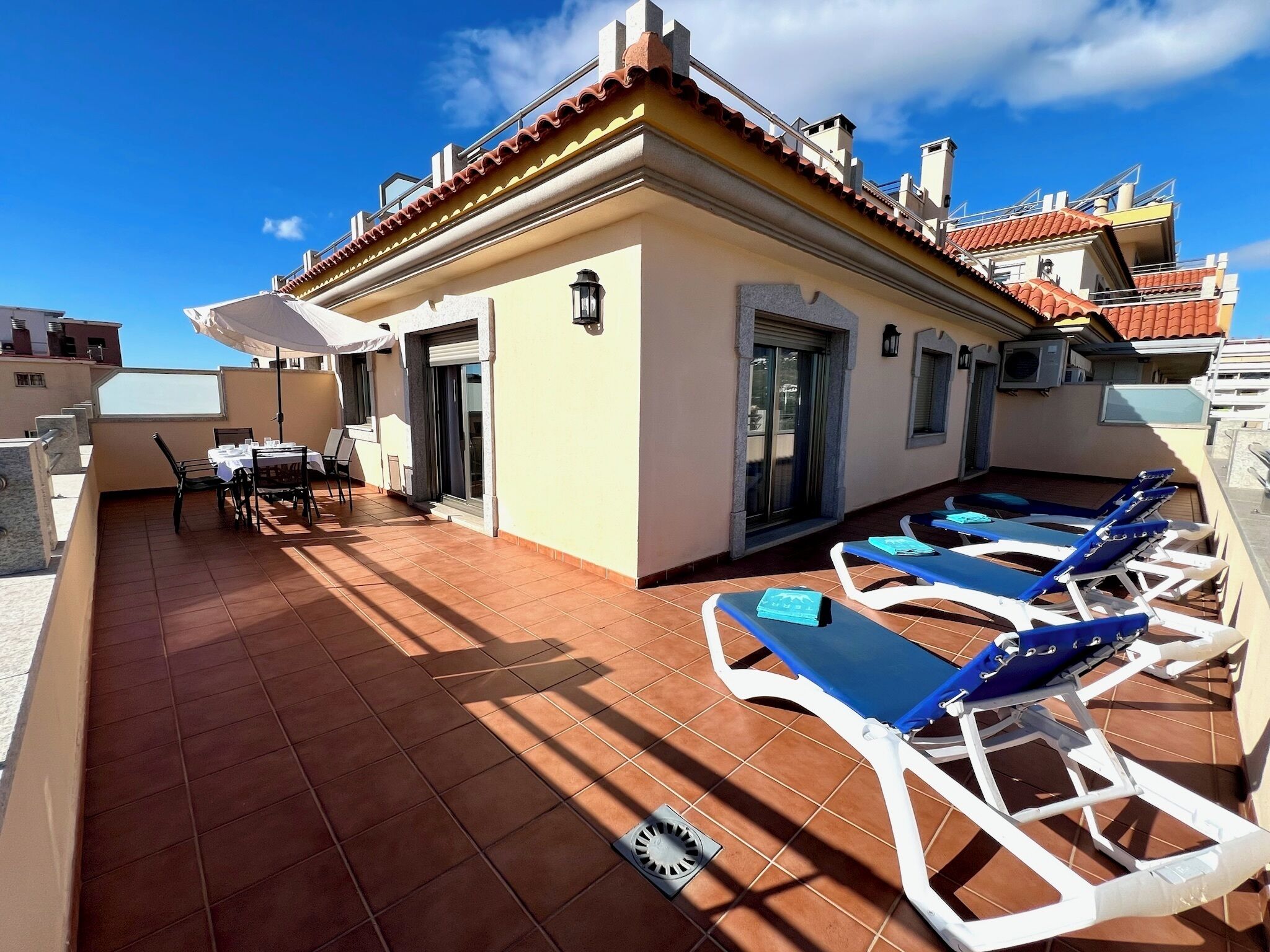 Une terrasse sur le toit avec un espace repas et des chaises longues.