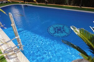 Una piscina al aire libre, sombrillas, sillones reclinables de piscina