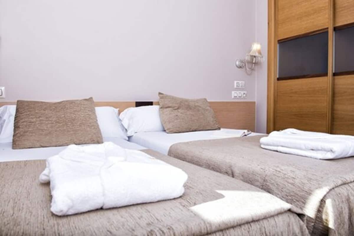 A hotel room with two beds, each with a white and brown pillow, and a neatly folded white towel on the bed.