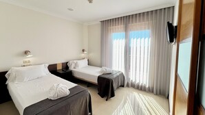 A hotel room with two beds, a small table, a TV, and a window with curtains. - Mediterraneo Real Apartamentos Turísticos (Fuengirola)