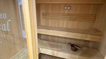 A sauna room with wooden benches and a small pot on the lower shelf.
