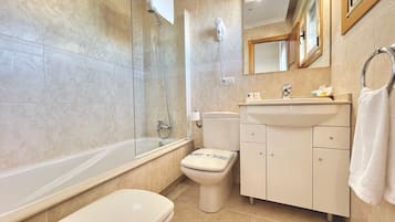 A modern bathroom with a glass-enclosed shower, a standalone toilet, a vanity with a mirror, and a bathtub.