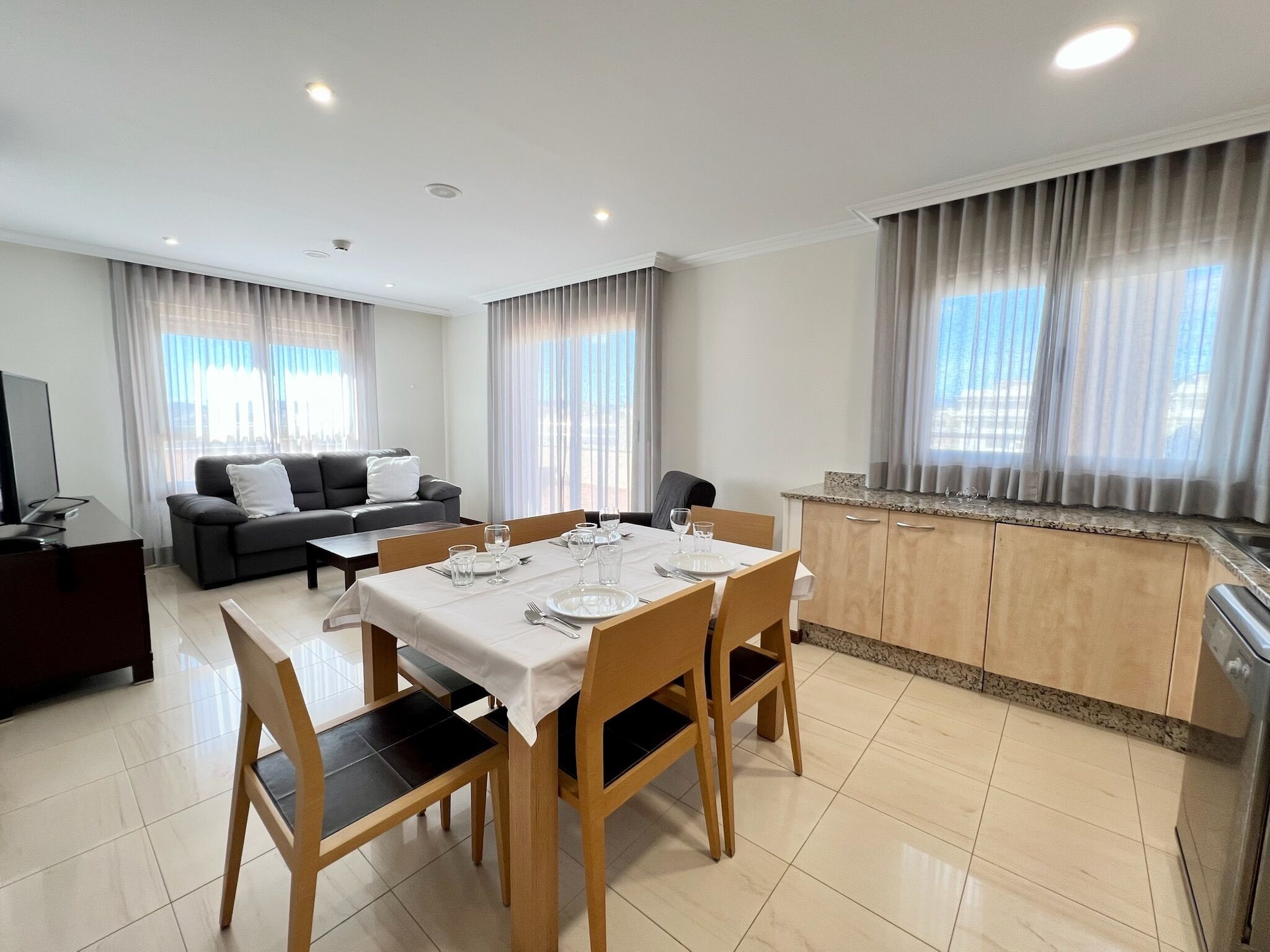 Een moderne woonkamer met een eethoek, een bank en een keuken.