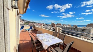 A terrace with a table set for two, overlooking a cityscape and the sea. - Mediterraneo Real Apartamentos Turísticos (Fuengirola)