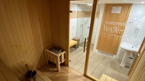 A sauna room with wooden benches and a small table with a bucket. - Mediterraneo Real Apartamentos Turísticos (Fuengirola)